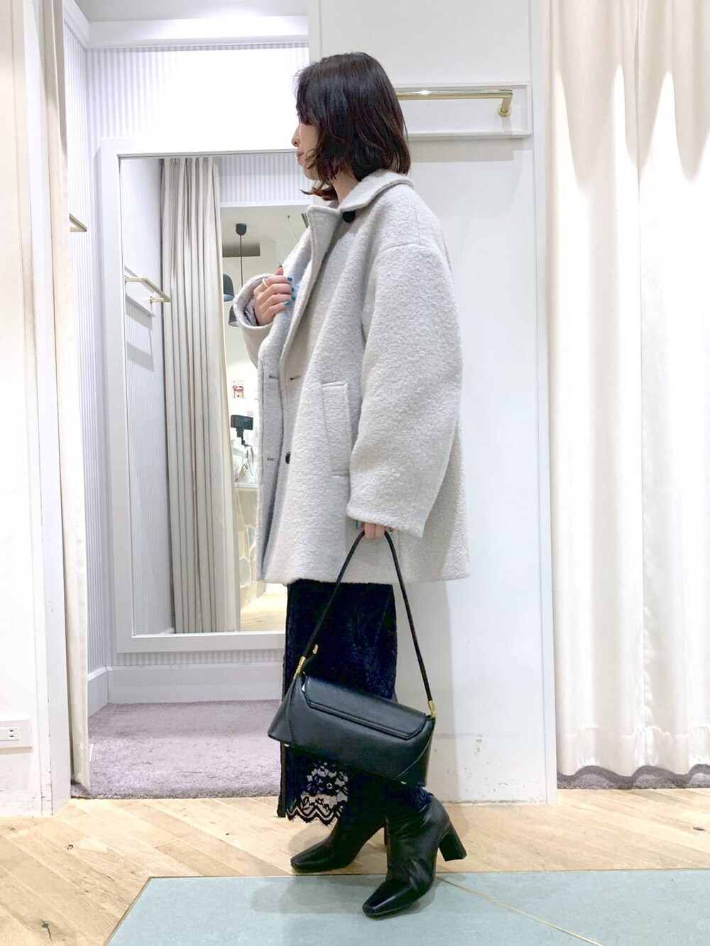 ブラック系のショルダーバッグ、グレー系のピーコート、ブラック系のブーツを着用したレディースの秋コーディネートの3枚目の写真