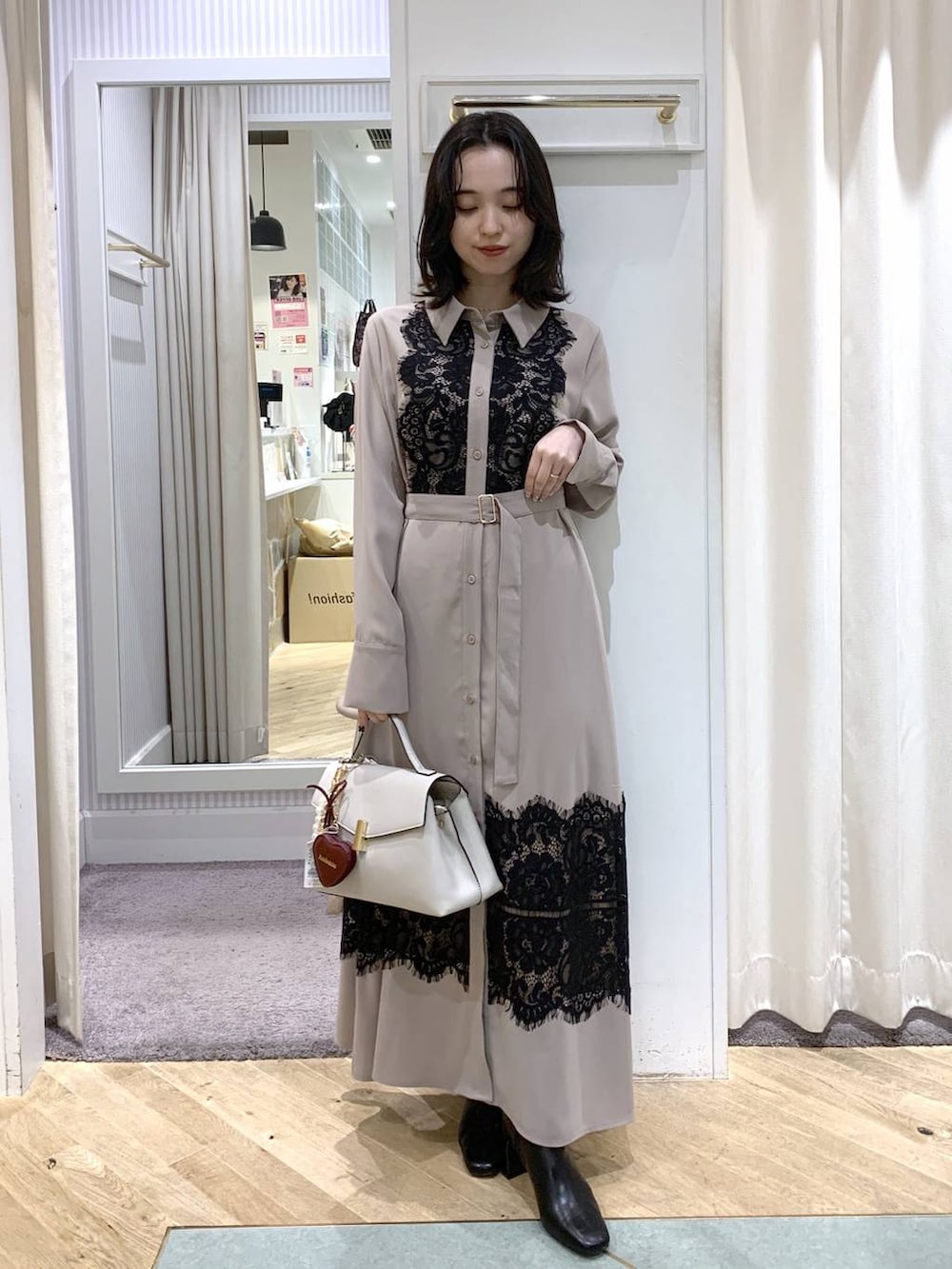 レッド系のピーコート、ブラック系のブーツ、ホワイト系のハンドバッグを着用したレディースの冬コーディネートの4枚目の写真