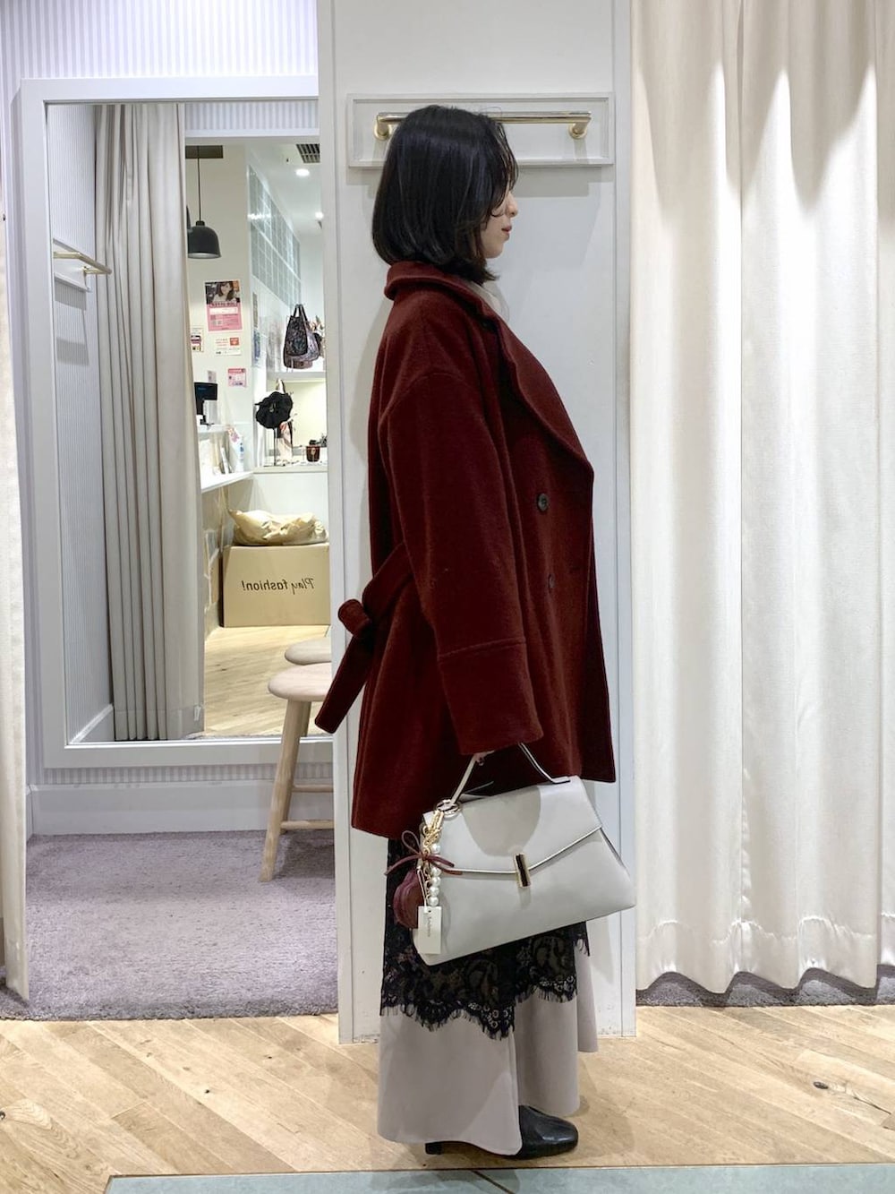 レッド系のピーコート、ブラック系のブーツ、ホワイト系のハンドバッグを着用したレディースの冬コーディネートの6枚目の写真