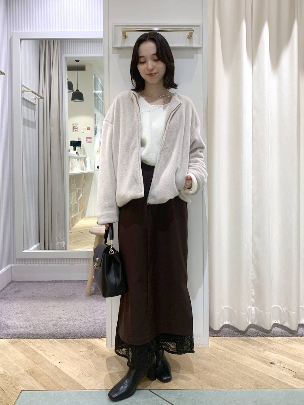 ベージュ系のブルゾン、ブラック系のブーツ、ブラック系のハンドバッグを着用したレディースの秋コーディネートの2枚目の写真