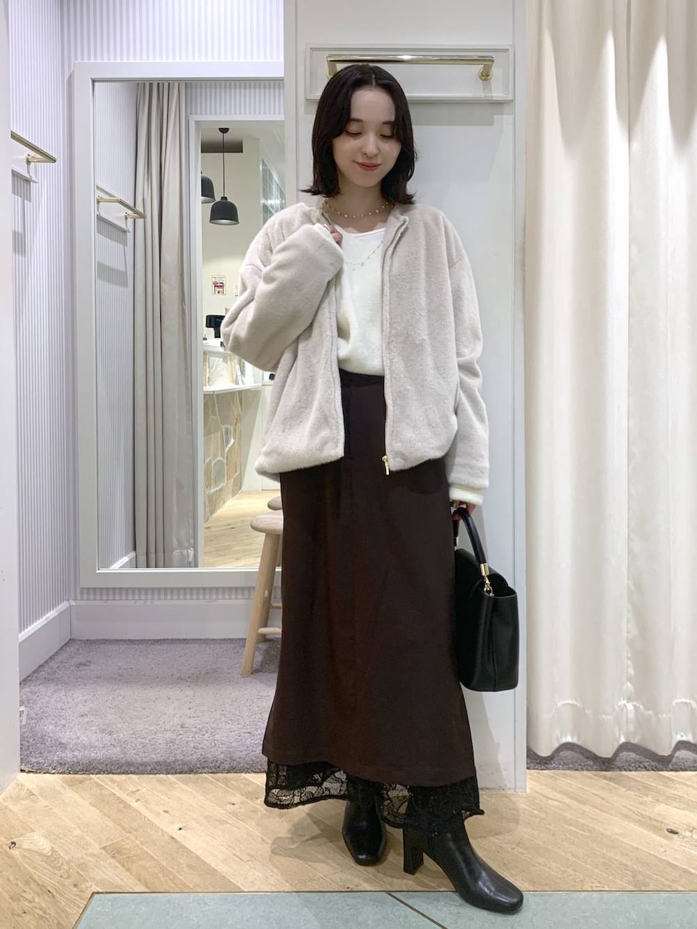 ベージュ系のブルゾン、ブラック系のブーツ、ブラック系のハンドバッグを着用したレディースの秋コーディネートの3枚目の写真