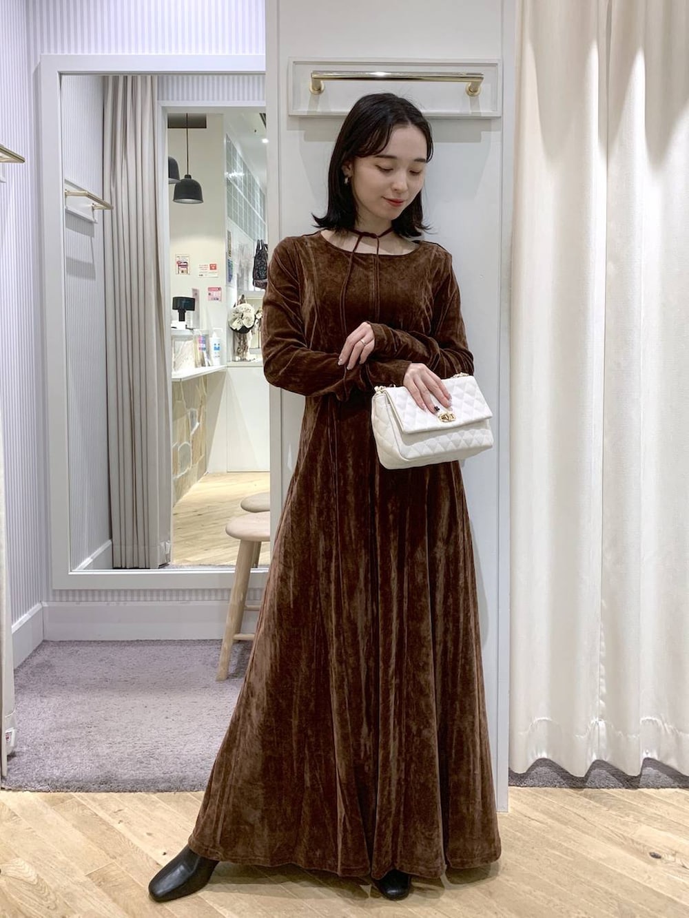 ブラック系のブーツ、ホワイト系のショルダーバッグ、ブラウン系のワンピースを着用したレディースの秋コーディネートの7枚目の写真