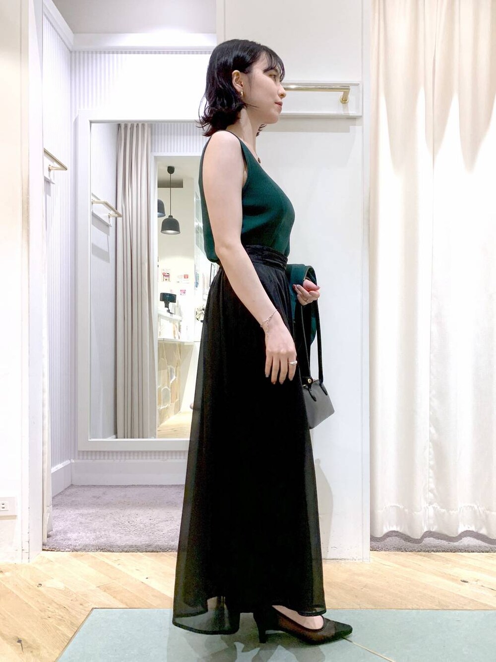 グレー系のスカート、ブラック系のボストンバッグ、グリーン系のカーディガン/ボレロを着用したレディースの夏コーディネートの8枚目の写真