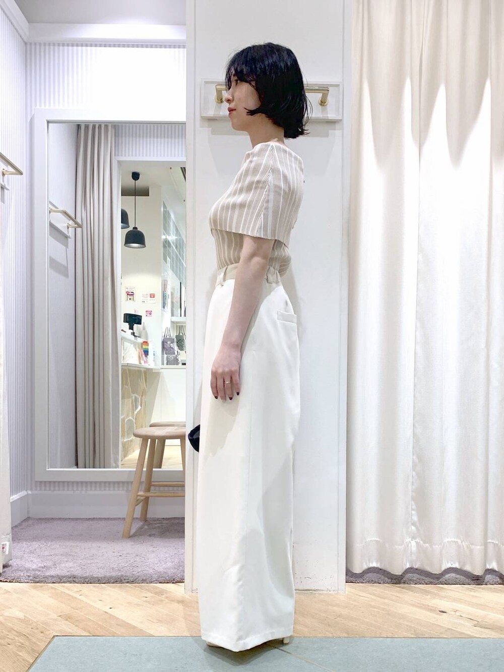 ベージュ系のかごバッグ、ホワイト系のサンダル、ホワイト系のスラックスを着用したレディースの夏コーディネートの3枚目の写真