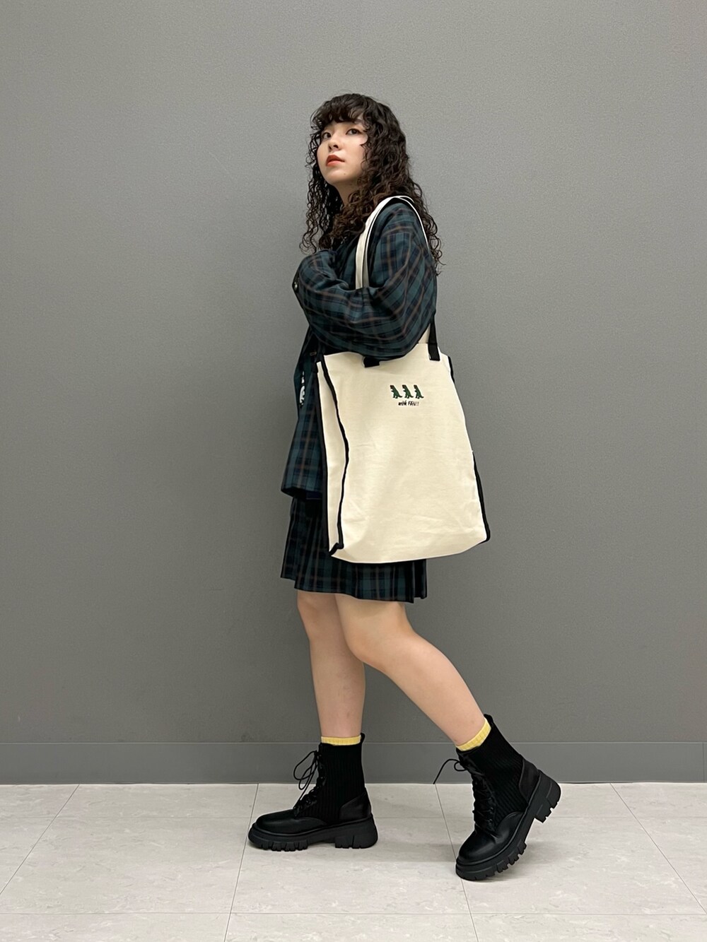 グリーン系のテーラードジャケット、ブラック系のトートバッグ、グリーン系のスカートを着用したレディースの秋コーディネートの2枚目の写真