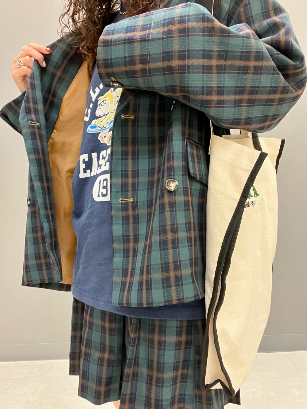 グリーン系のテーラードジャケット、ブラック系のトートバッグ、グリーン系のスカートを着用したレディースの秋コーディネートの7枚目の写真