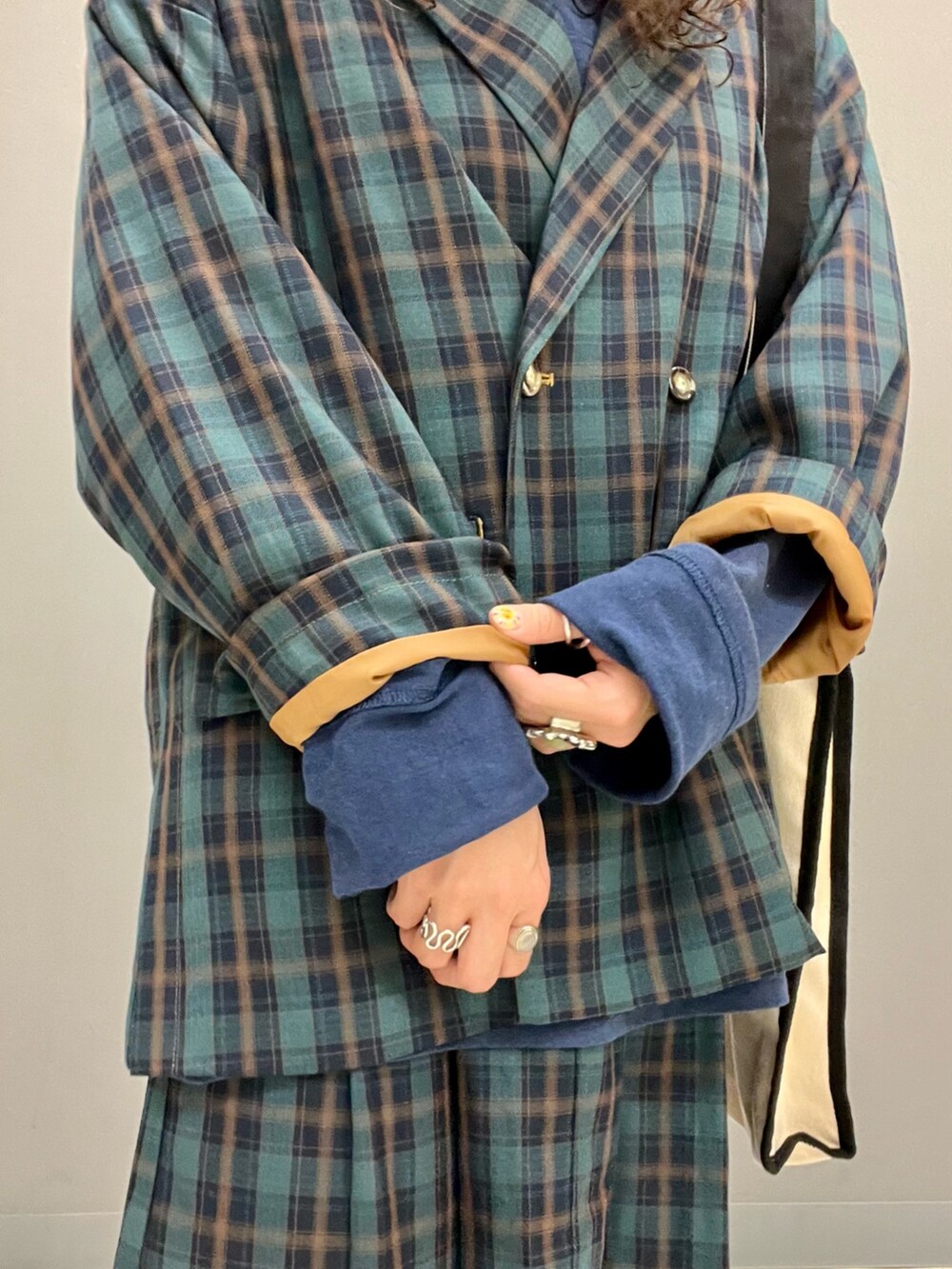 グリーン系のテーラードジャケット、ブラック系のトートバッグ、グリーン系のスカートを着用したレディースの秋コーディネートの5枚目の写真