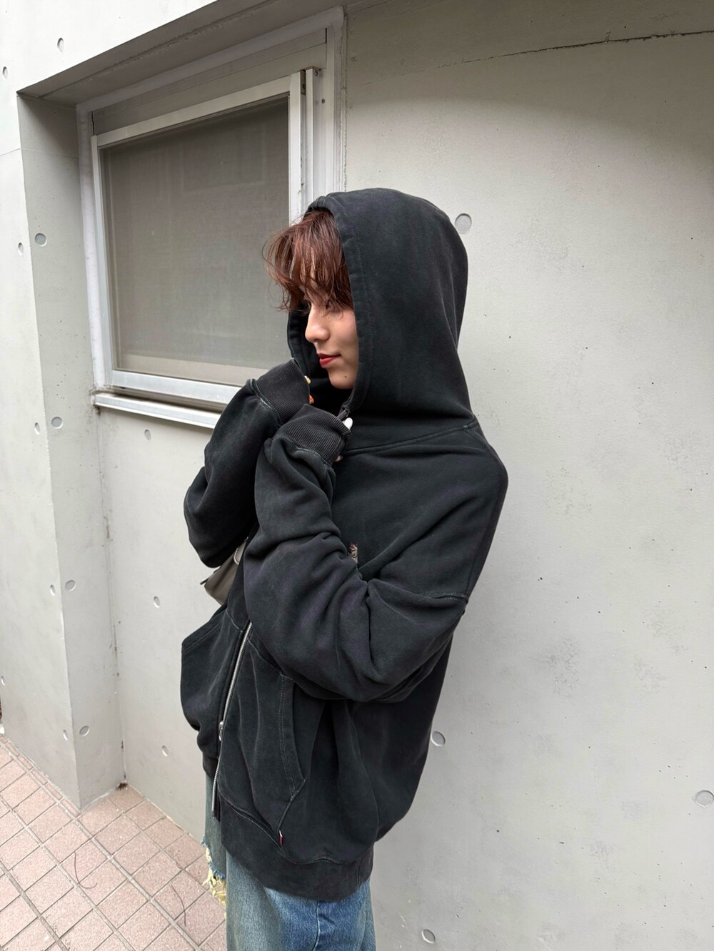 ブラック系のパーカー、レッド系のTシャツ/カットソー、ブルー系のデニムパンツを着用したレディースの秋コーディネートの3枚目の写真