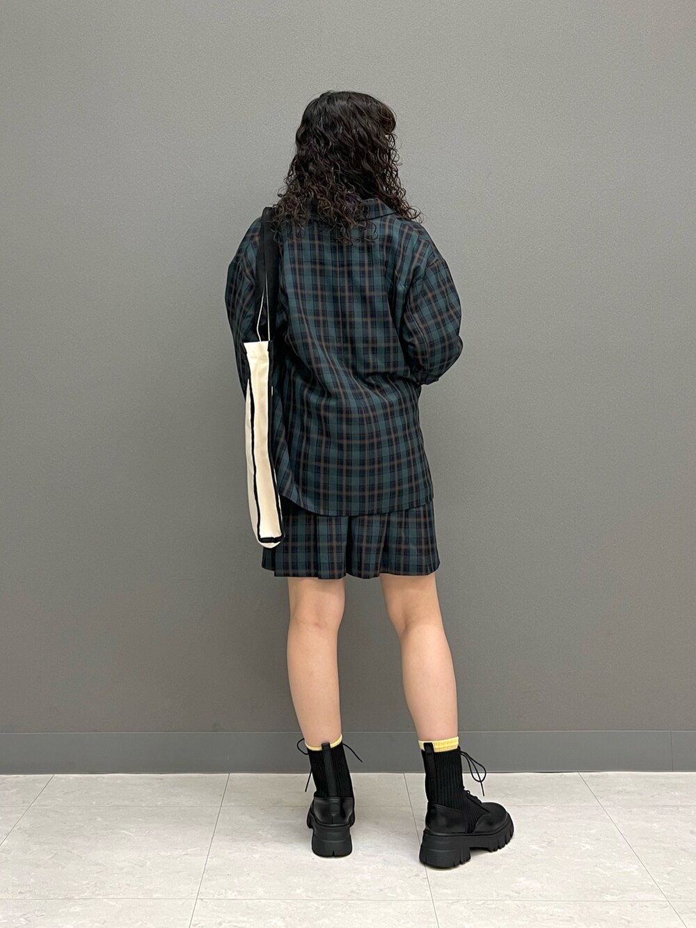 グリーン系のテーラードジャケット、ブラック系のトートバッグ、グリーン系のスカートを着用したレディースの秋コーディネートの3枚目の写真