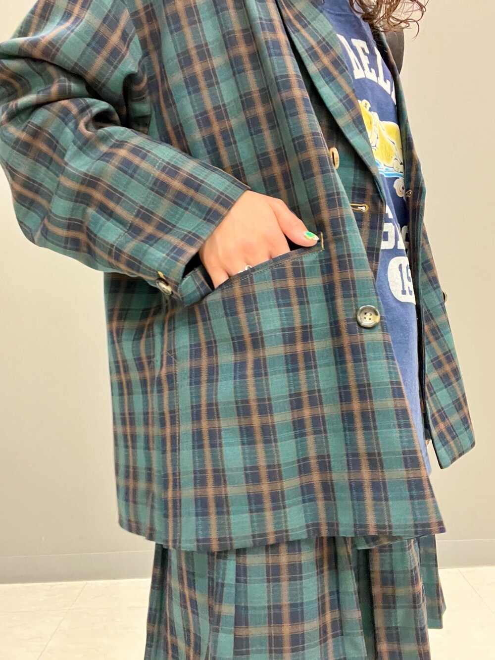 グリーン系のテーラードジャケット、ブラック系のトートバッグ、グリーン系のスカートを着用したレディースの秋コーディネートの6枚目の写真