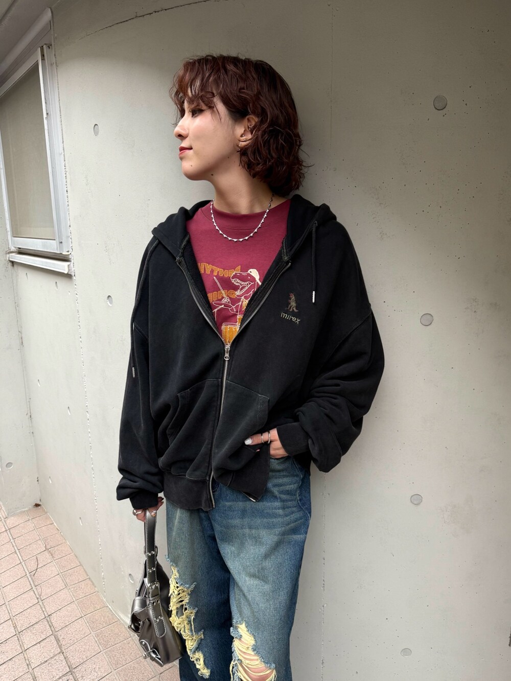 ブラック系のパーカー、レッド系のTシャツ/カットソー、ブルー系のデニムパンツを着用したレディースの秋コーディネートの2枚目の写真