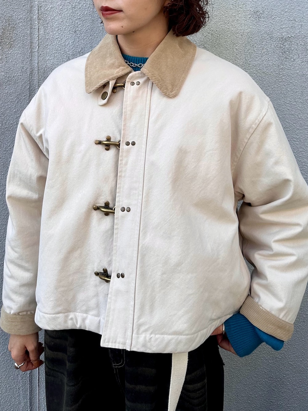 ブルー系のニット/セーター、ブラック系のデニムパンツ、ホワイト系のブルゾンを着用したレディースの秋コーディネートの4枚目の写真