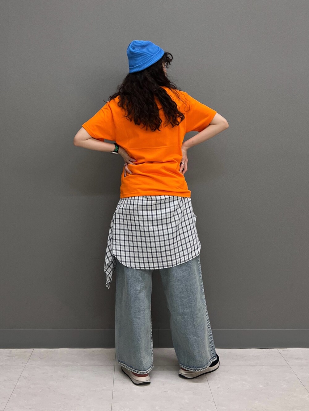 オレンジ系のTシャツ/カットソー、ホワイト系のシャツ/ブラウス、ブルー系のデニムパンツを着用したレディースの春コーディネートの5枚目の写真