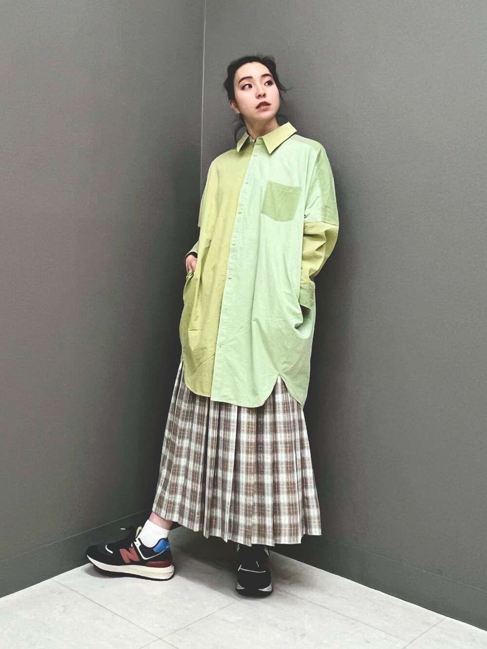 ベージュ系のスカート、グリーン系のワンピースを着用したレディースの春コーディネートの2枚目の写真