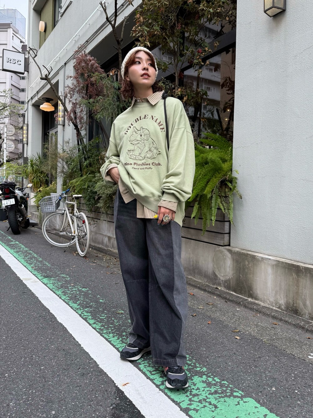 グリーン系のTシャツ/カットソー、ベージュ系のシャツ/ブラウス、ブラック系のデニムパンツを着用したレディースの秋コーディネートの2枚目の写真