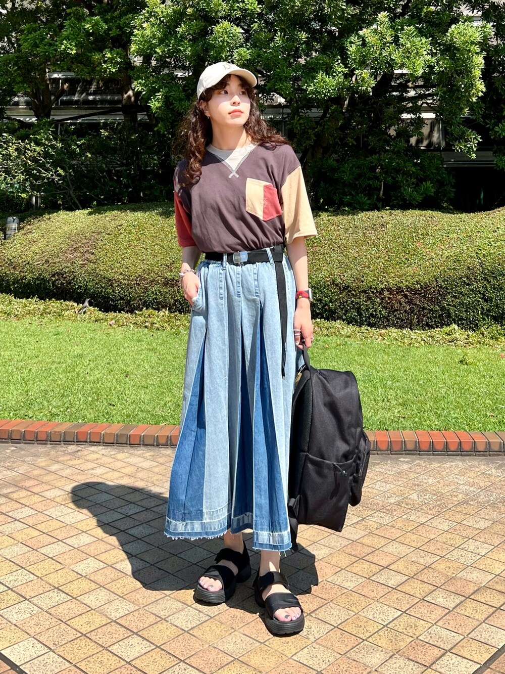 ブルー系のデニムスカート、ブラック系のTシャツ/カットソー、ブラック系のベルトを着用したレディースの夏コーディネートの2枚目の写真