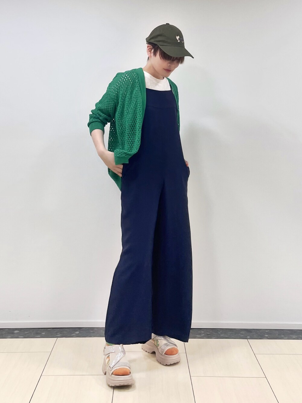 グリーン系のカーディガン/ボレロ、ブルー系のオールインワン・サロペット、ベージュ系のサンダルを着用したレディースの春コーディネートの2枚目の写真