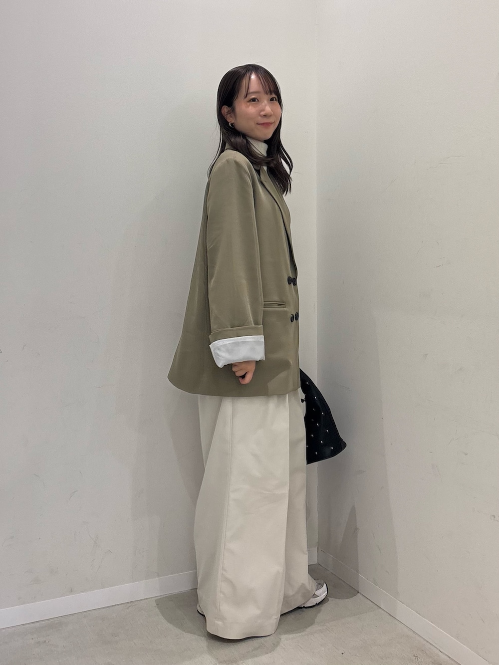 ベージュ系のテーラードジャケット、ホワイト系のチノパンツ、ブラック系のハンドバッグを着用したレディースの冬コーディネートの3枚目の写真