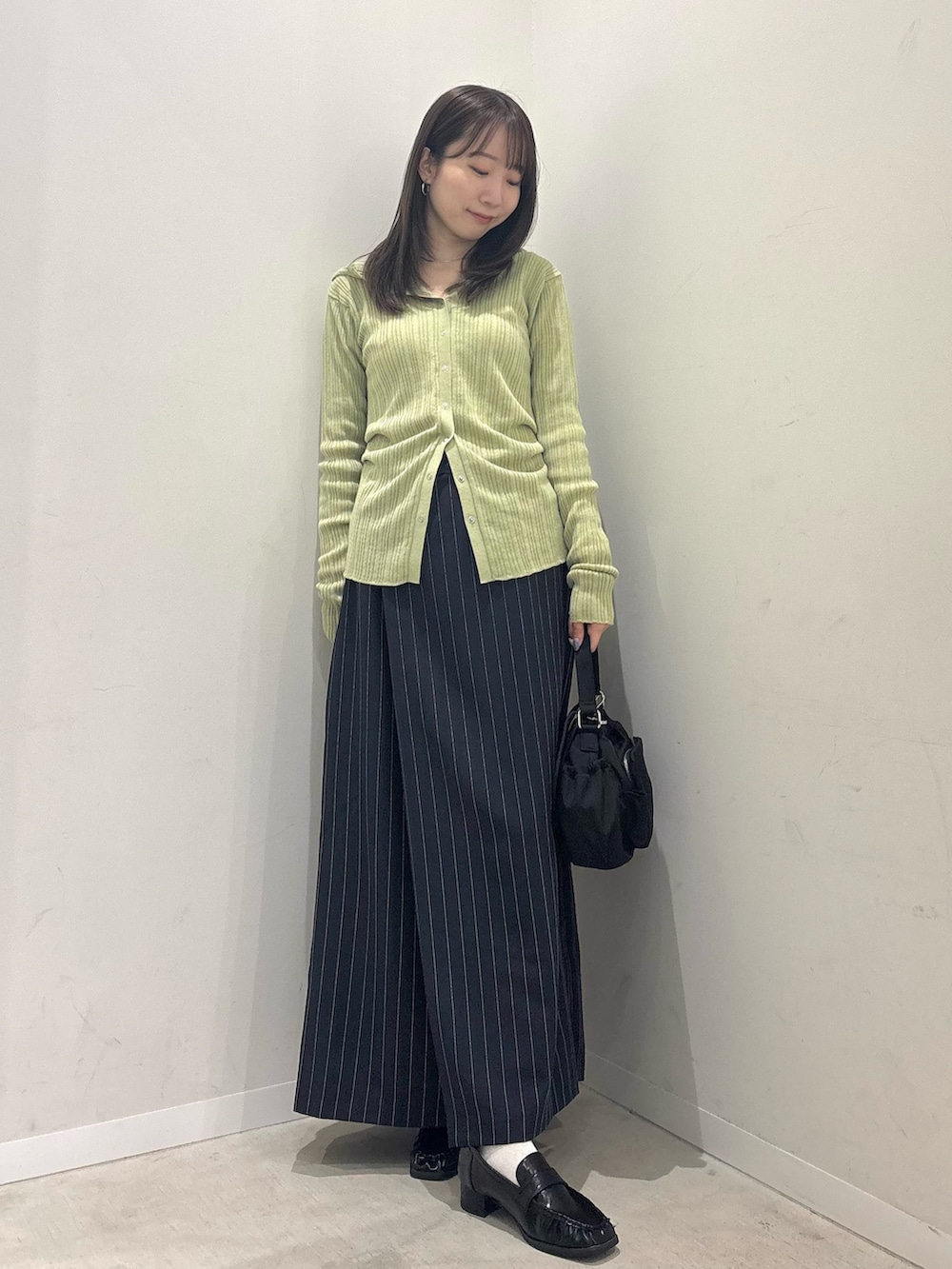 ベージュ系のニット/セーター、ブルー系のスカート、ブラック系のローファーを着用したレディースの春コーディネートの2枚目の写真