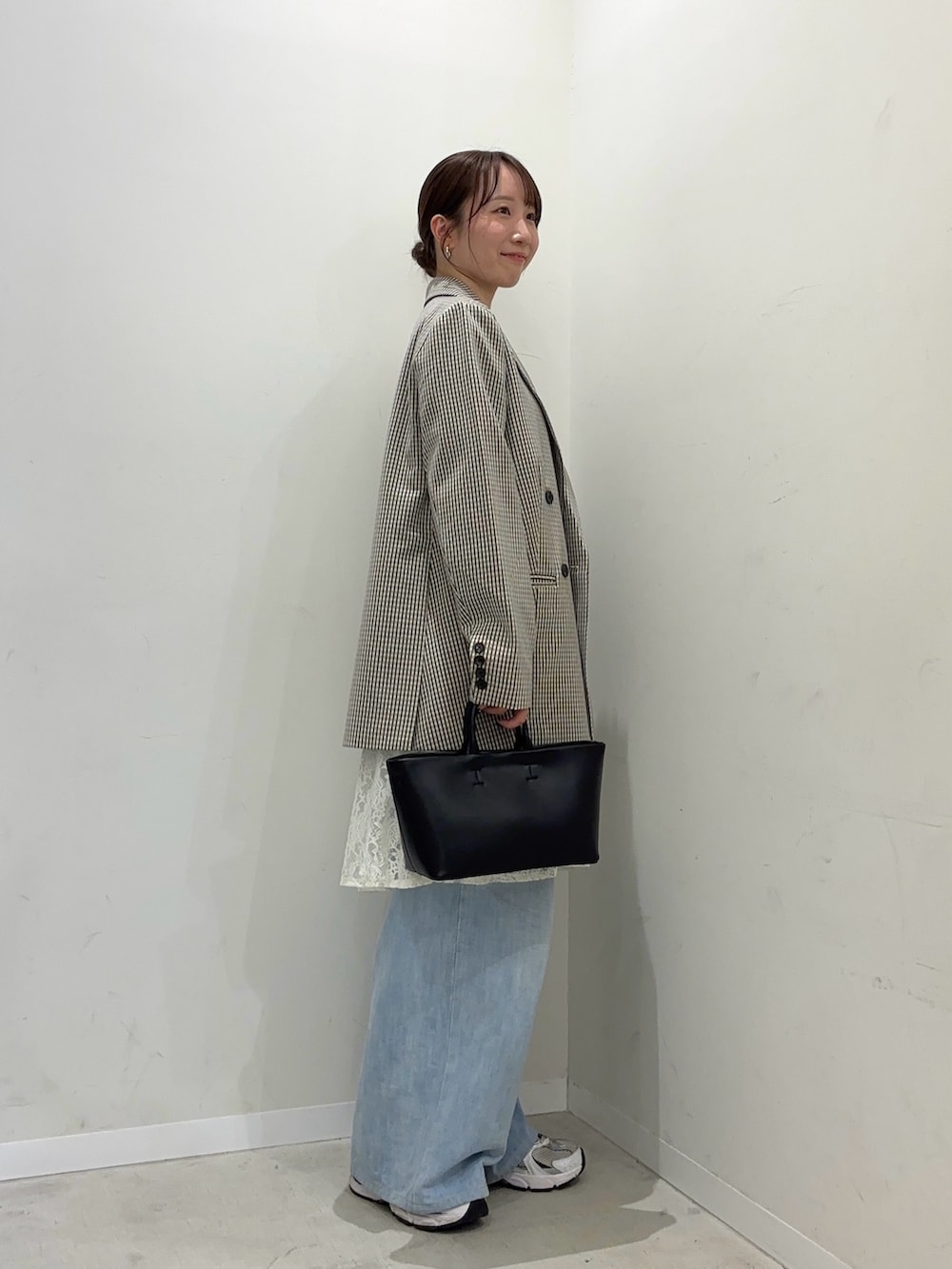 ベージュ系のテーラードジャケット、ホワイト系のキャミソール、ブラック系のトートバッグを着用したレディースの冬コーディネートの2枚目の写真