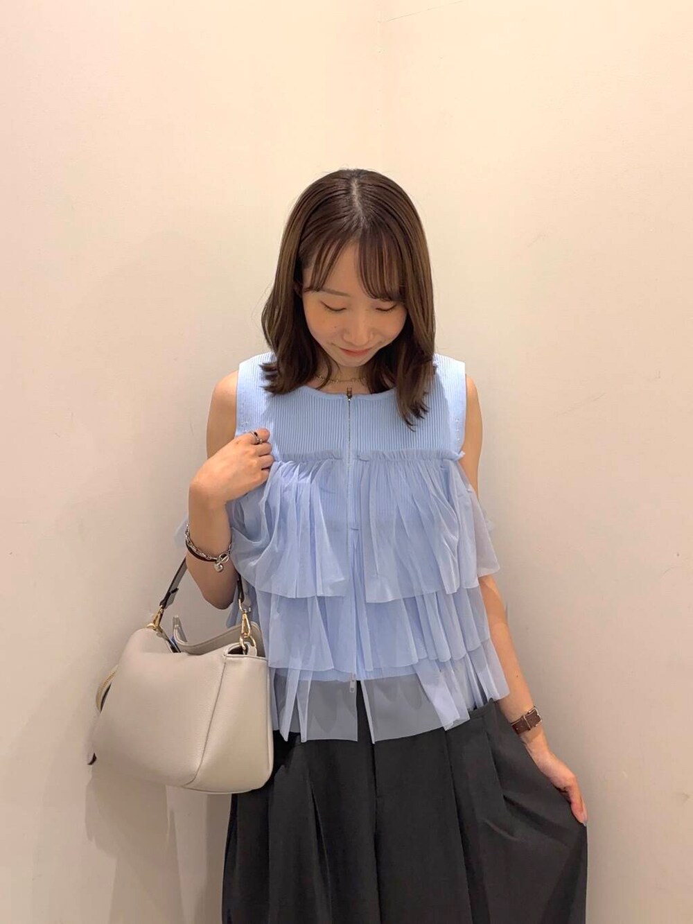 グレー系のショルダーバッグ、ブルー系のニット/セーター、ホワイト系のサンダルを着用したレディースの夏コーディネートの4枚目の写真