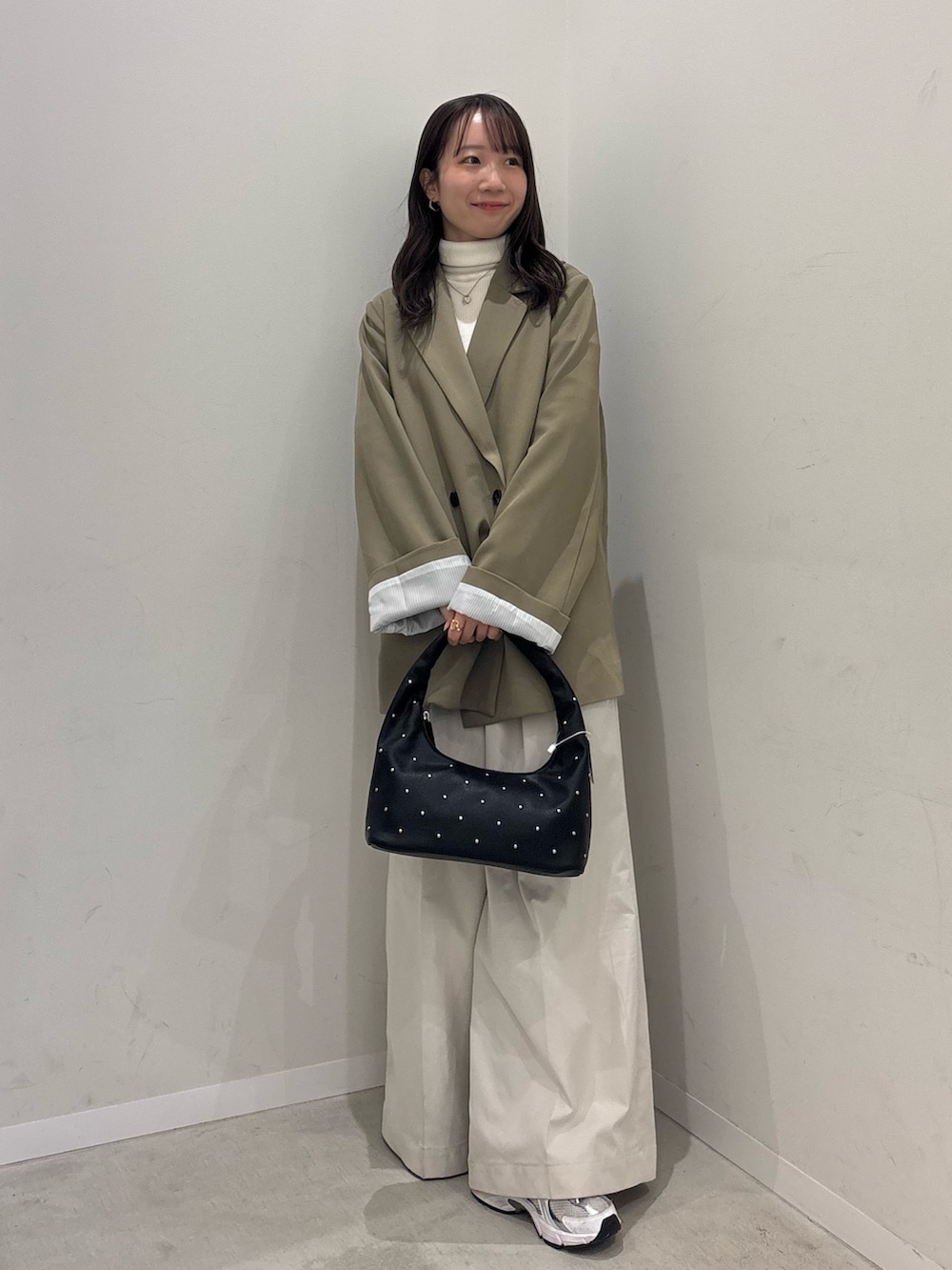 ベージュ系のテーラードジャケット、ホワイト系のチノパンツ、ブラック系のハンドバッグを着用したレディースの冬コーディネートの2枚目の写真