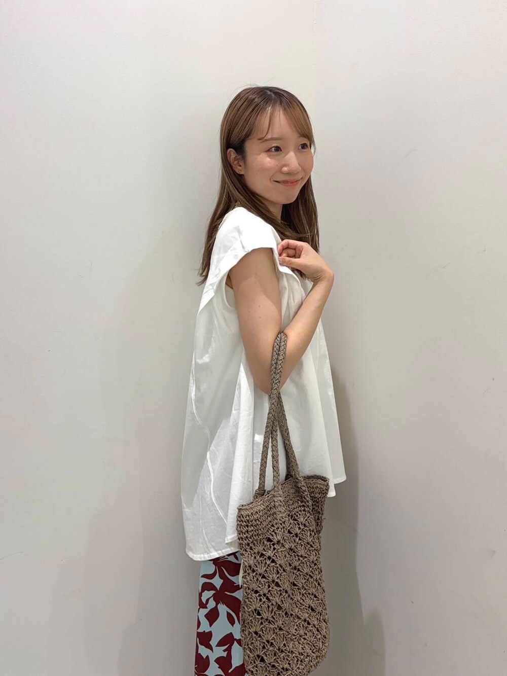 グレー系のトートバッグ、ホワイト系のサンダル、ホワイト系のTシャツ/カットソーを着用したレディースの春コーディネートの2枚目の写真