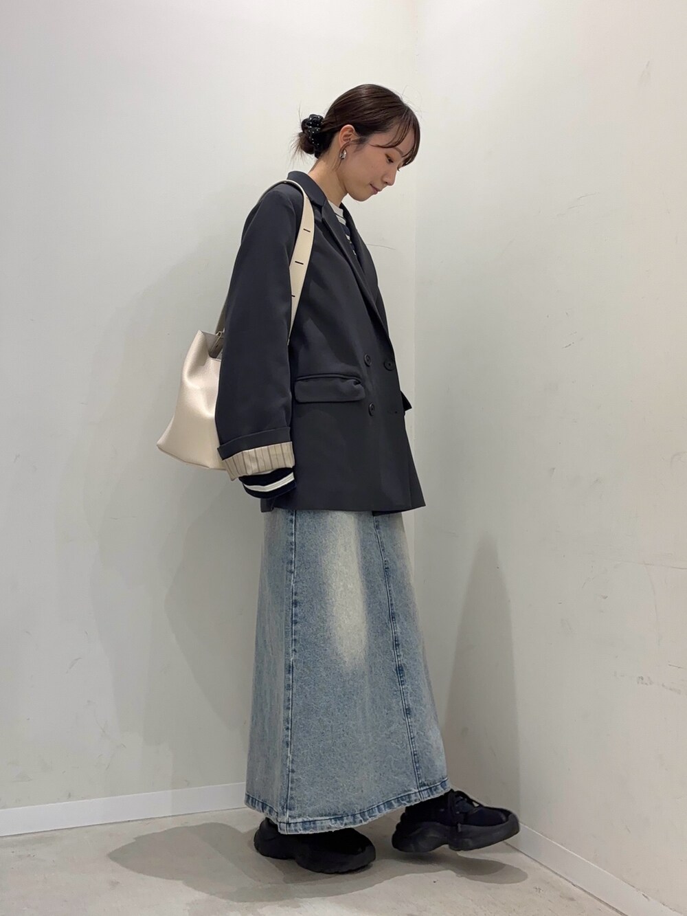 グレー系のテーラードジャケット、ブルー系のスカート、ブラック系のスニーカーを着用したレディースの冬コーディネートの3枚目の写真