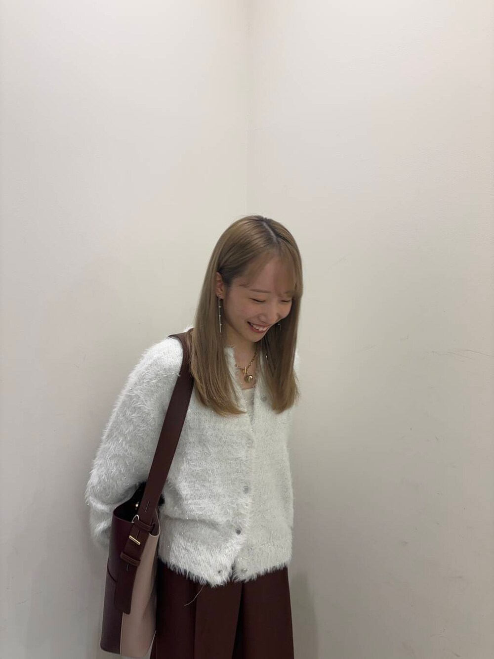 ホワイト系のタンクトップ、ブラウン系のショルダーバッグ、グレー系のパンプスを着用したレディースの秋コーディネートの3枚目の写真