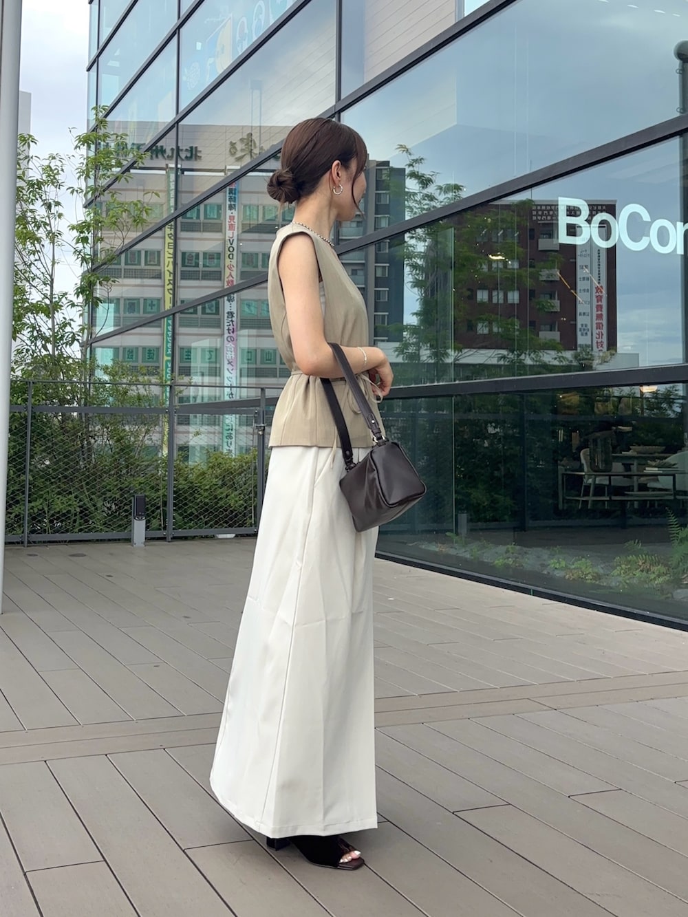 ベージュ系のベスト、ホワイト系のスカート、ブラウン系のショルダーバッグを着用したレディースの夏コーディネートの2枚目の写真