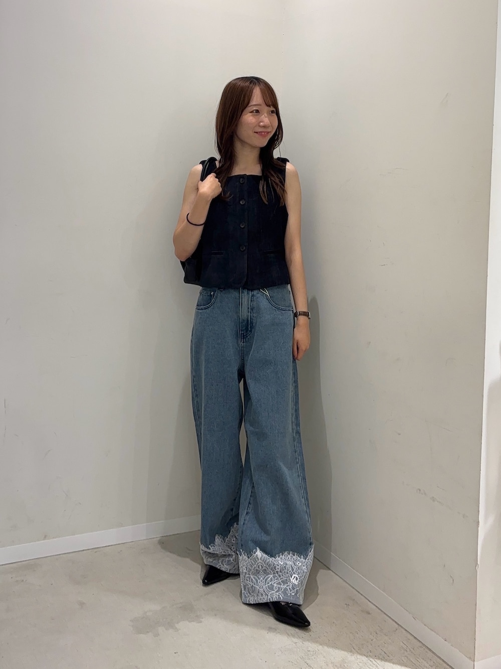 ブルー系のダウンベスト、ブルー系のデニムパンツ、ブラック系のパンプスを着用したレディースの夏コーディネートの2枚目の写真