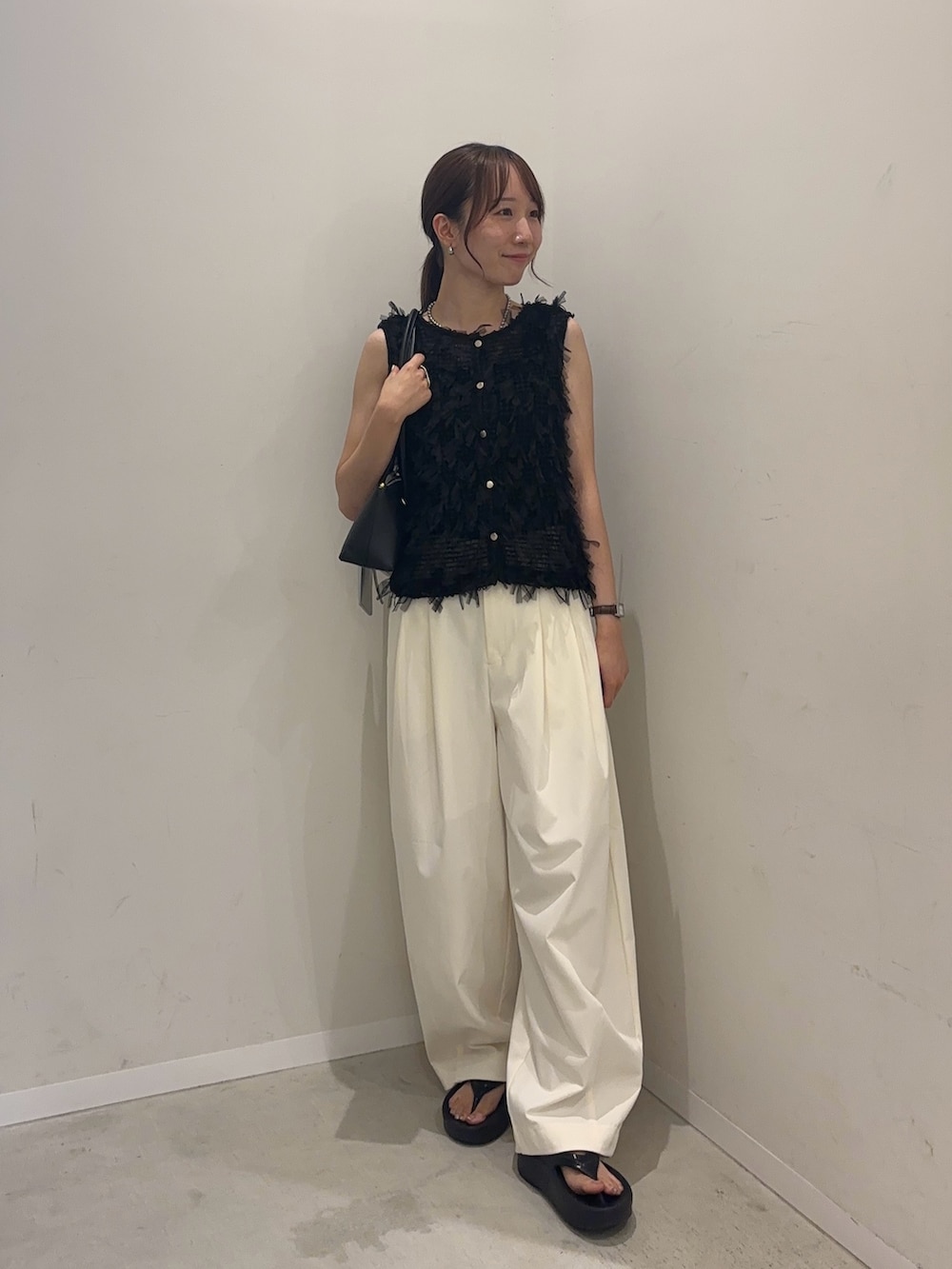 ブラック系のベスト、ホワイト系のその他パンツ、ブラック系のサンダルを着用したレディースの夏コーディネートの2枚目の写真