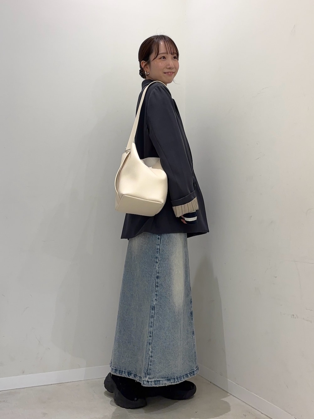 グレー系のテーラードジャケット、ブルー系のスカート、ブラック系のスニーカーを着用したレディースの冬コーディネートの2枚目の写真