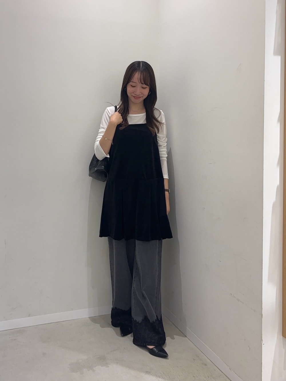ブラック系のチュニック、ホワイト系のTシャツ/カットソー、グレー系のデニムパンツを着用したレディースの秋コーディネートの2枚目の写真