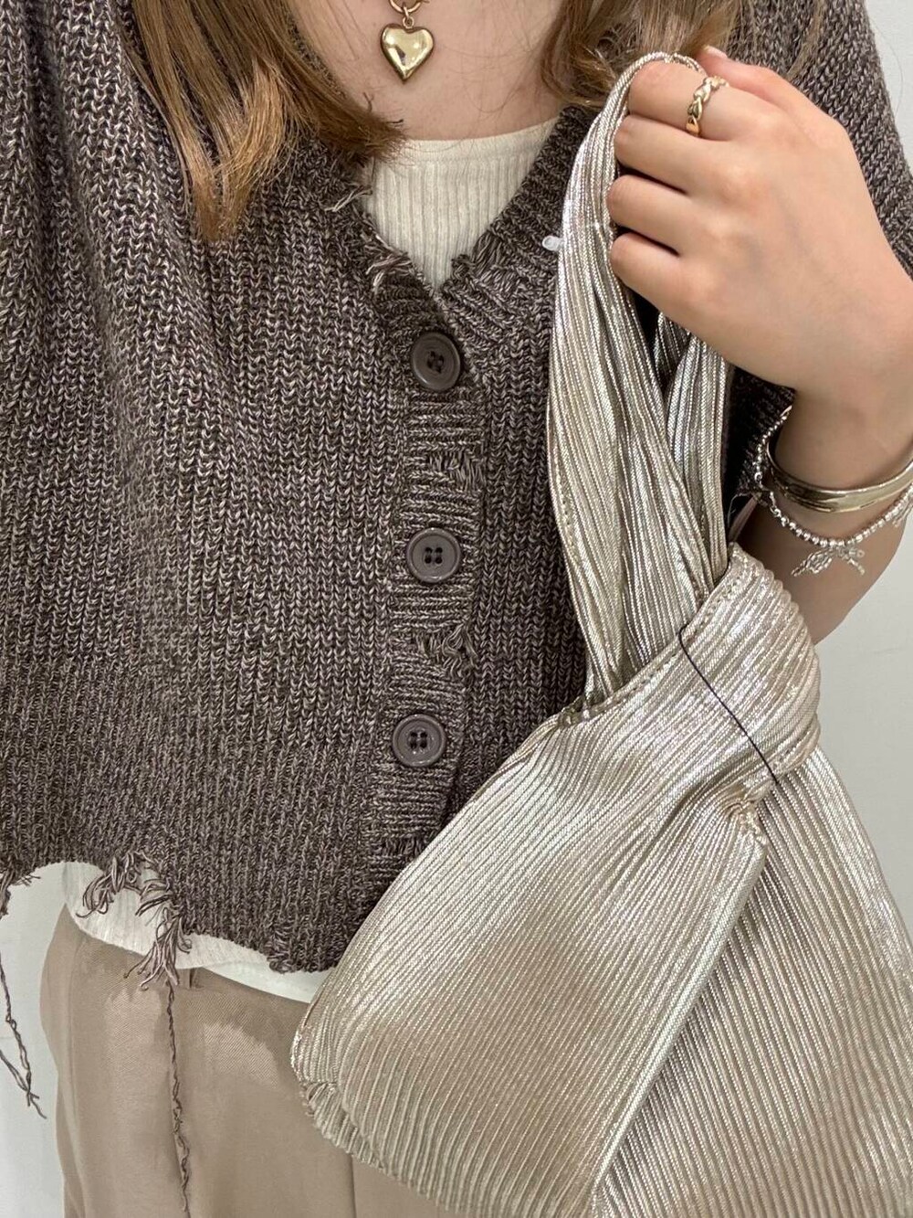 ゴールド系のハンドバッグ、ブラウン系のベスト、ベージュ系のその他パンツを着用したレディースの夏コーディネートの2枚目の写真