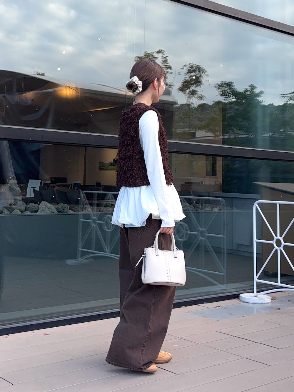 ブラウン系のベスト、ホワイト系のTシャツ/カットソー、ブラウン系のデニムパンツを着用したレディースの秋コーディネートの2枚目の写真