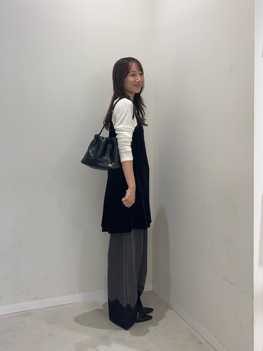 ブラック系のチュニック、ホワイト系のTシャツ/カットソー、グレー系のデニムパンツを着用したレディースの秋コーディネートの3枚目の写真
