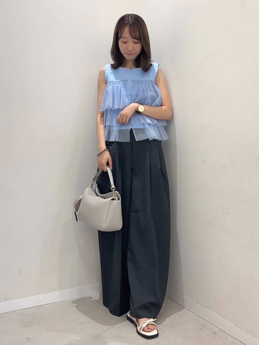 グレー系のショルダーバッグ、ブルー系のニット/セーター、ホワイト系のサンダルを着用したレディースの夏コーディネートの3枚目の写真