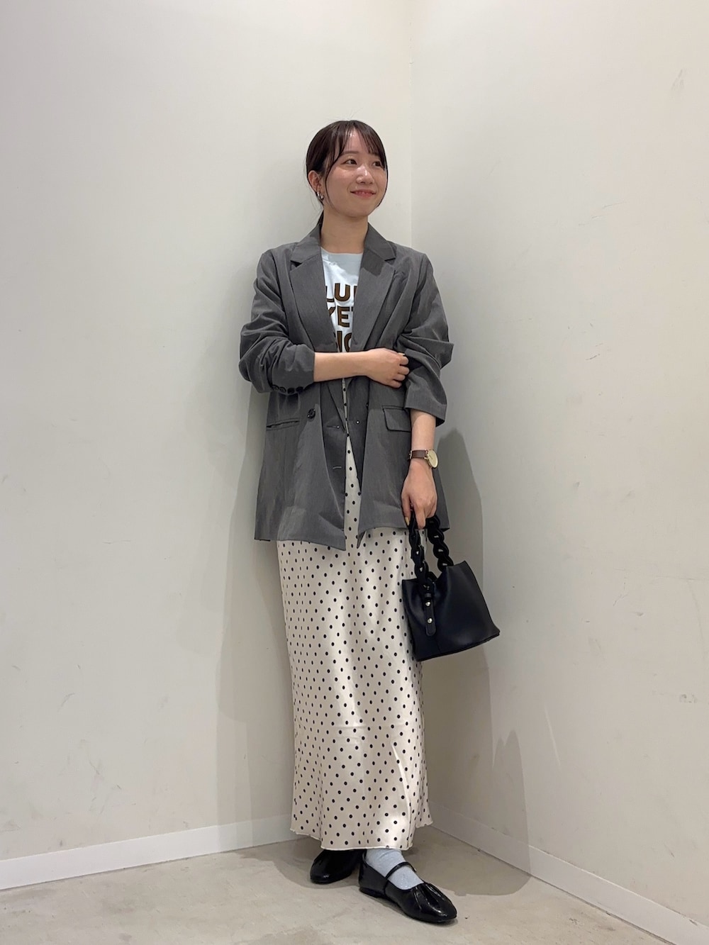 グレー系のテーラードジャケット、ホワイト系のスカート、ブラック系のパンプスを着用したレディースの春コーディネートの2枚目の写真