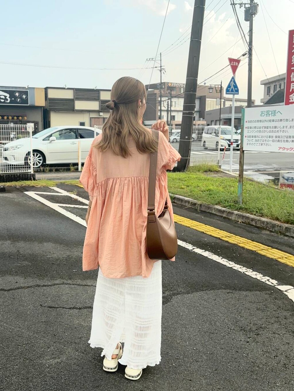 オレンジ系のワンピース、ホワイト系のスカート、ゴールド系のバングル/リストバンドを着用したレディースの夏コーディネートの4枚目の写真