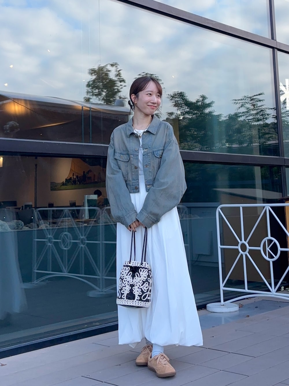 ブラウン系のデニムジャケット、ホワイト系のスカート、ベージュ系のスニーカーを着用したレディースの秋コーディネートの3枚目の写真