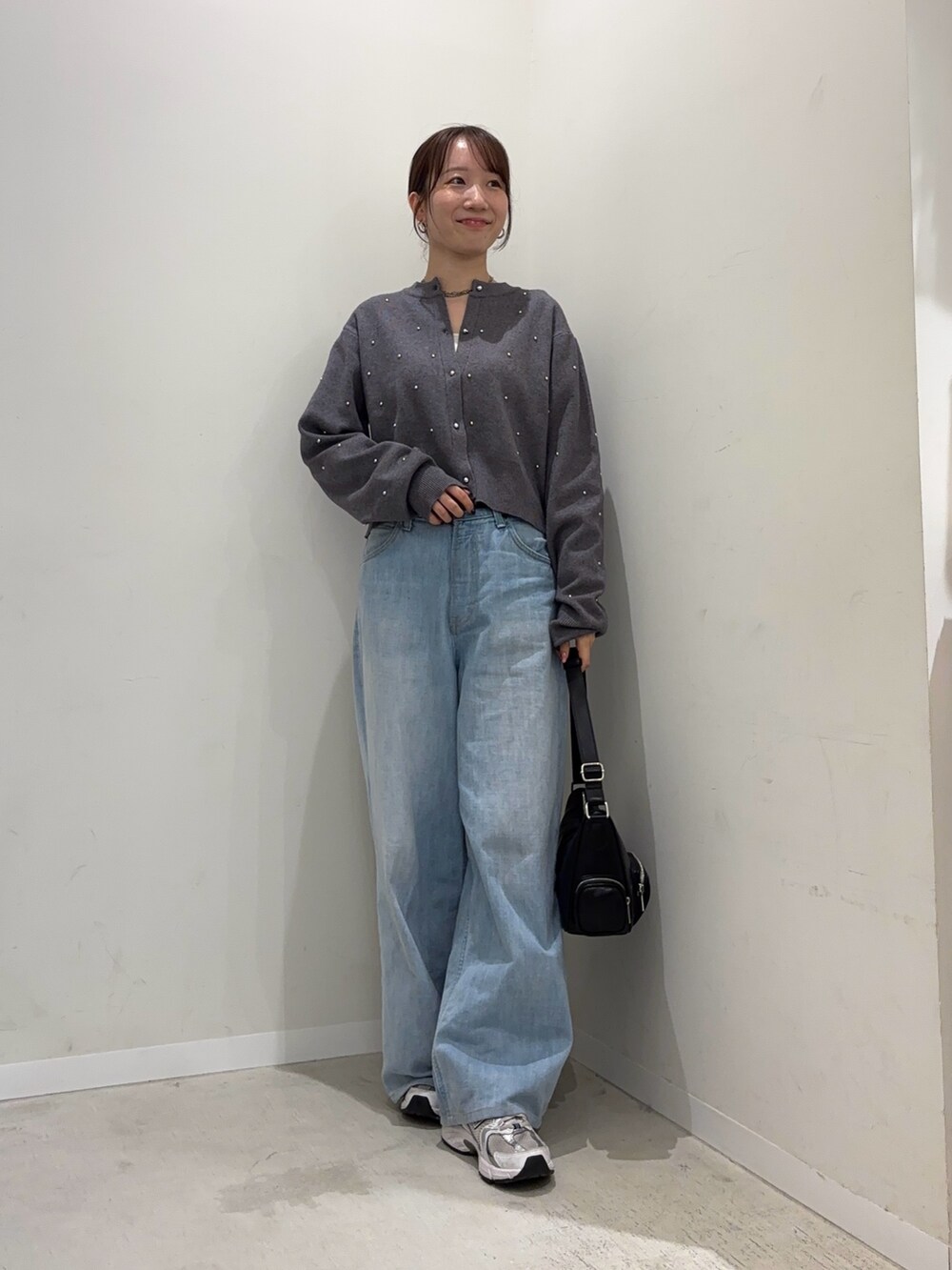 グレー系のカーディガン/ボレロ、ブルー系のデニムパンツ、ブラック系のショルダーバッグを着用したレディースの冬コーディネートの2枚目の写真