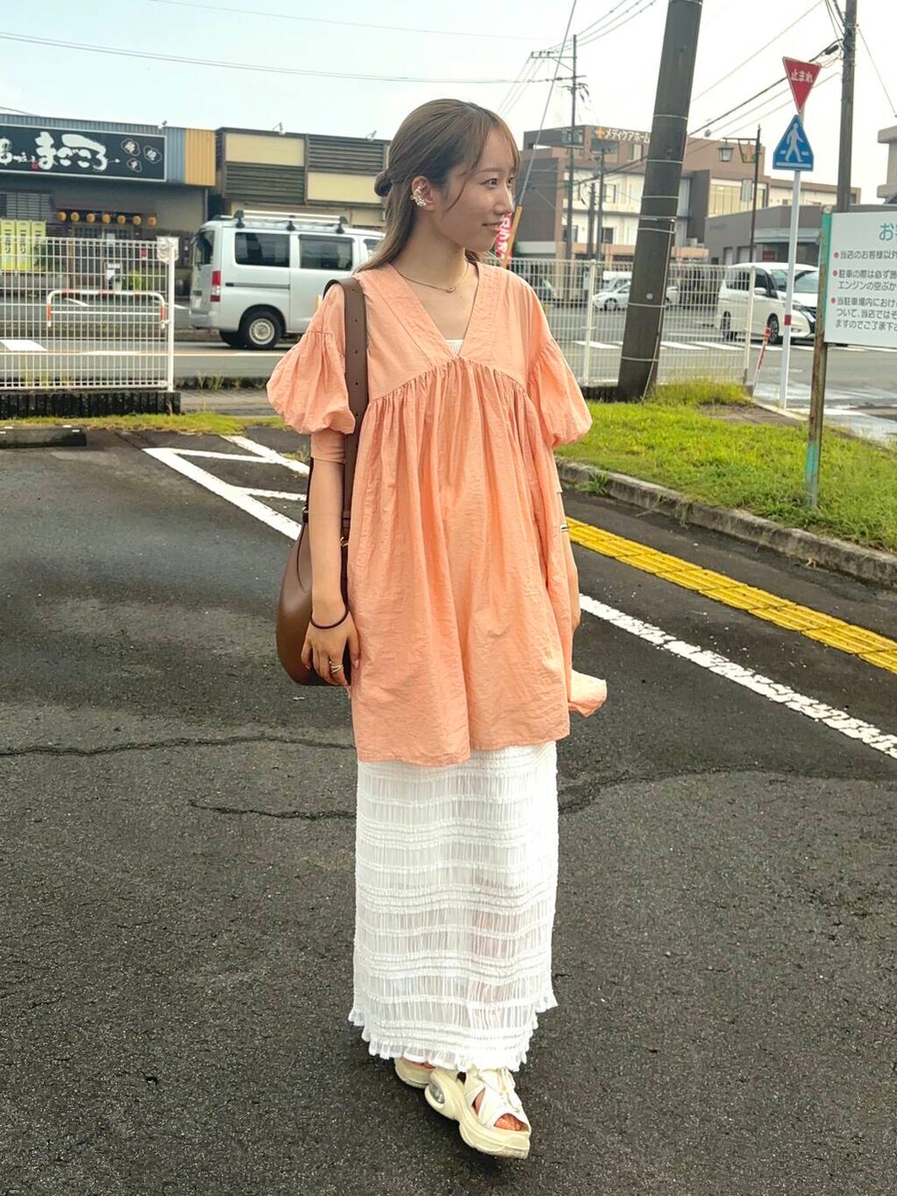 オレンジ系のワンピース、ホワイト系のスカート、ゴールド系のバングル/リストバンドを着用したレディースの夏コーディネートの5枚目の写真