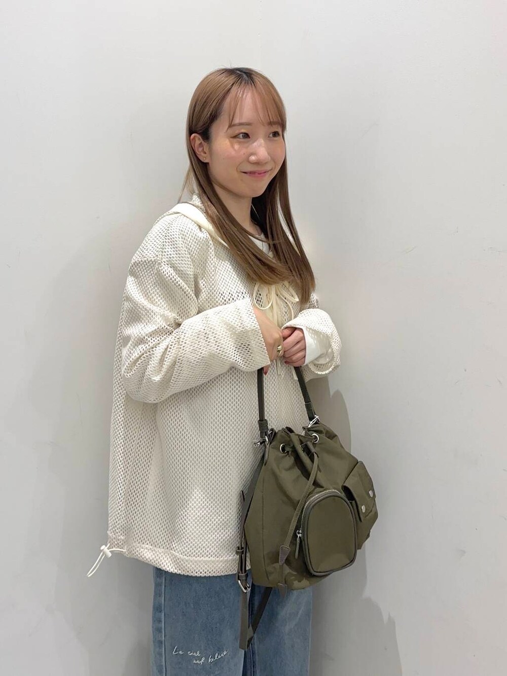 グリーン系のショルダーバッグ、その他のTシャツ/カットソー、ブルー系のデニムパンツを着用したレディースの春コーディネートの2枚目の写真