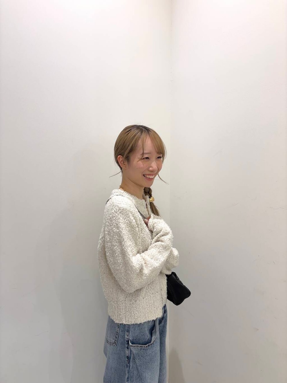 ブルー系のデニムパンツ、ブラック系のショルダーバッグ、ホワイト系のカーディガン/ボレロを着用したレディースの冬コーディネートの2枚目の写真