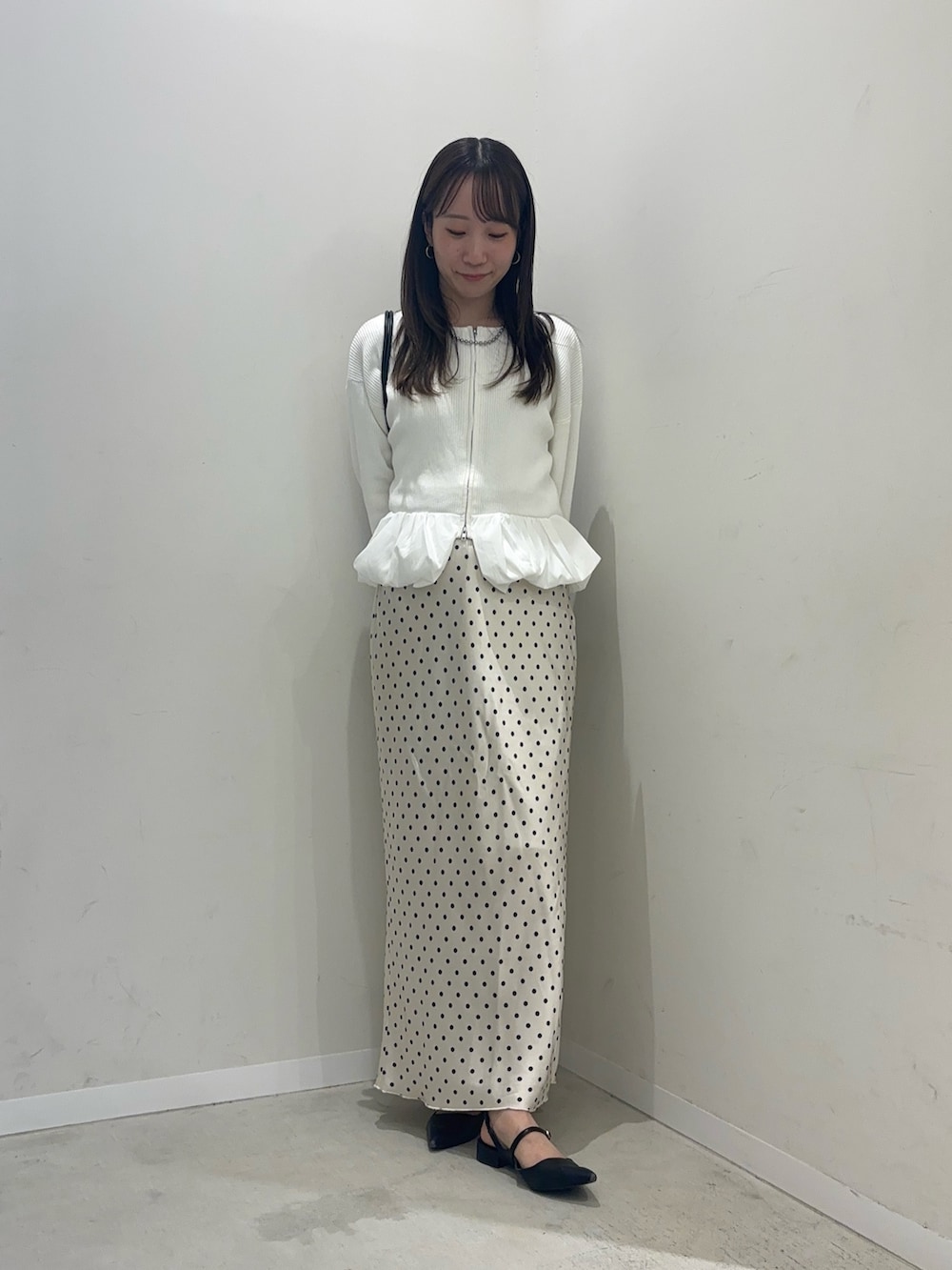 ホワイト系のカーディガン/ボレロ、ホワイト系のスカート、ブラック系のショルダーバッグを着用したレディースの秋コーディネートの2枚目の写真
