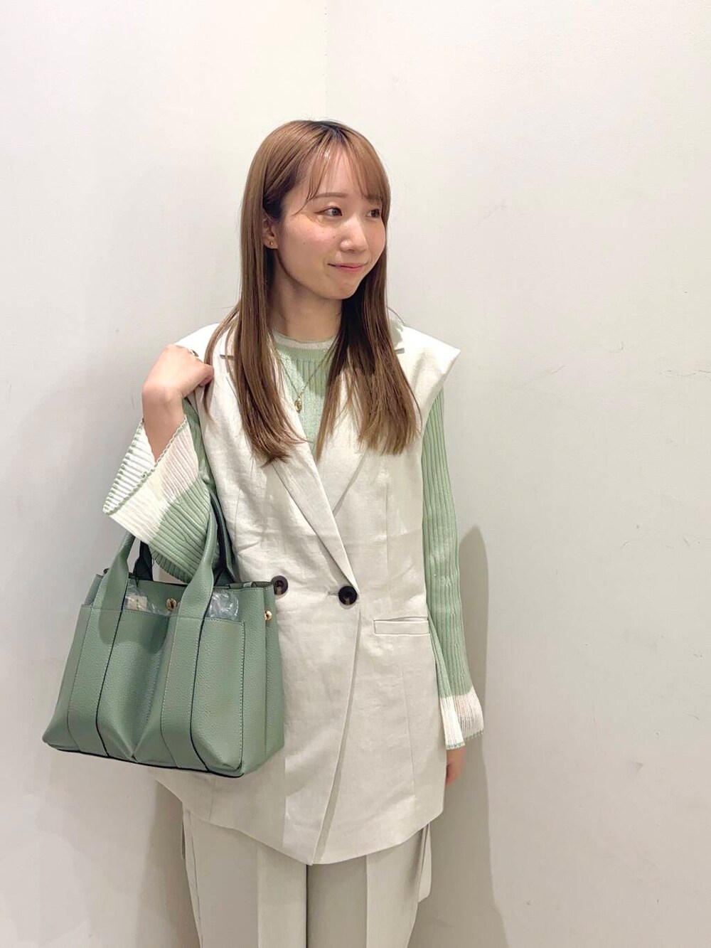 グリーン系のニット/セーター、グリーン系のトートバッグ、ホワイト系のバレエシューズを着用したレディースの春コーディネートの2枚目の写真