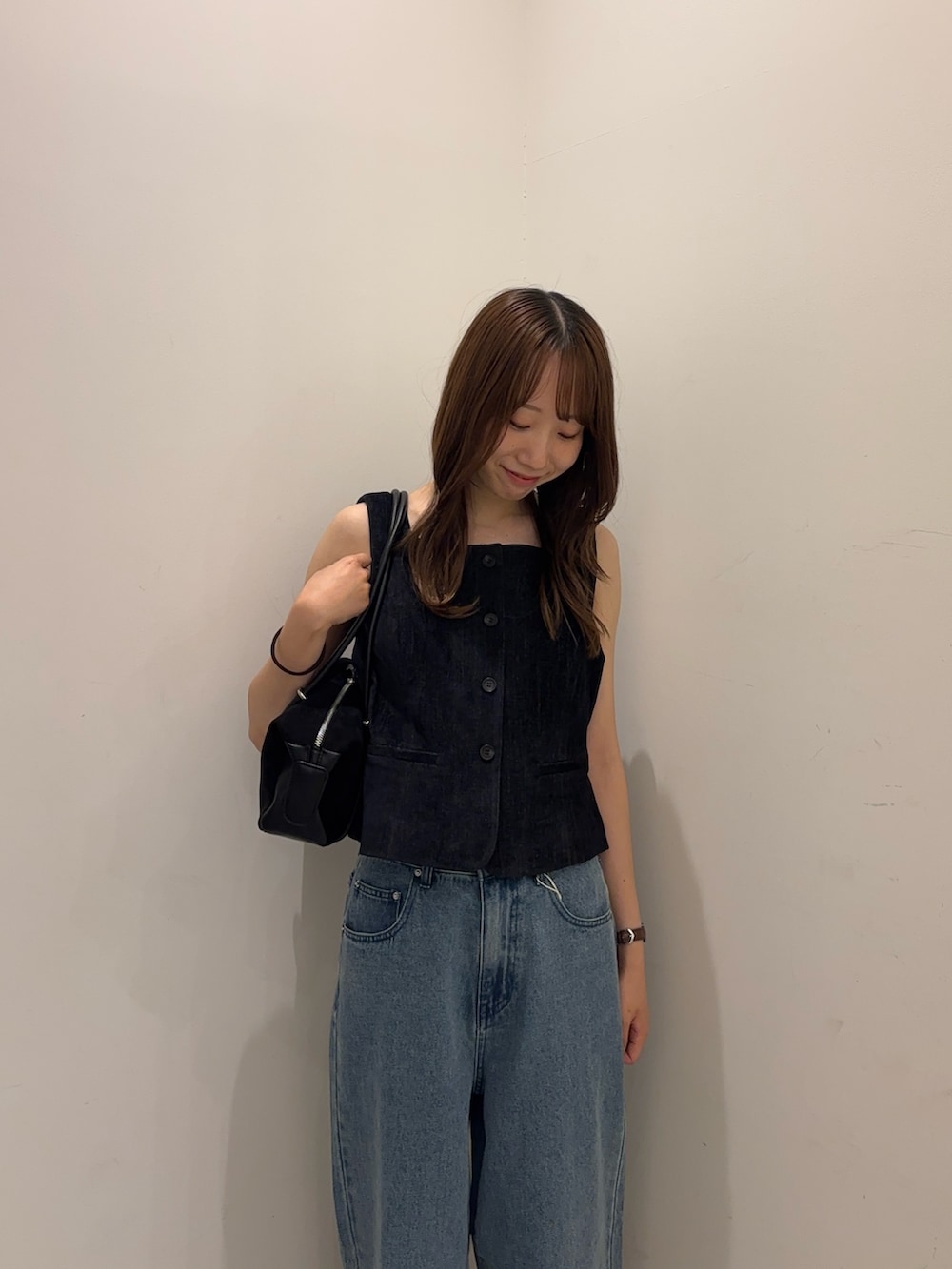 ブルー系のダウンベスト、ブルー系のデニムパンツ、ブラック系のパンプスを着用したレディースの夏コーディネートの3枚目の写真