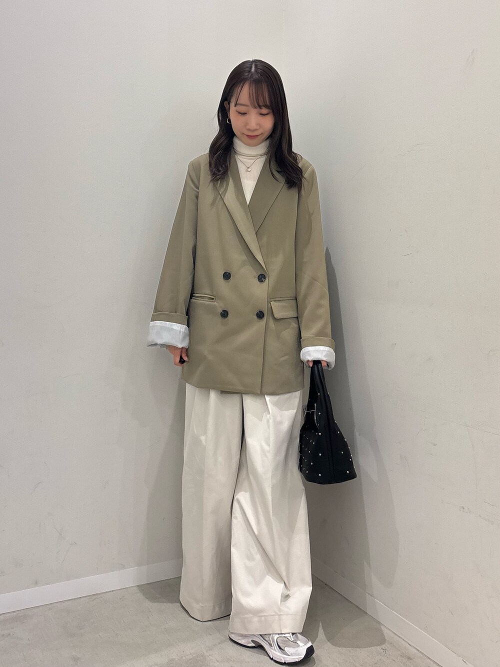 ベージュ系のテーラードジャケット、ホワイト系のチノパンツ、ブラック系のハンドバッグを着用したレディースの冬コーディネートの4枚目の写真