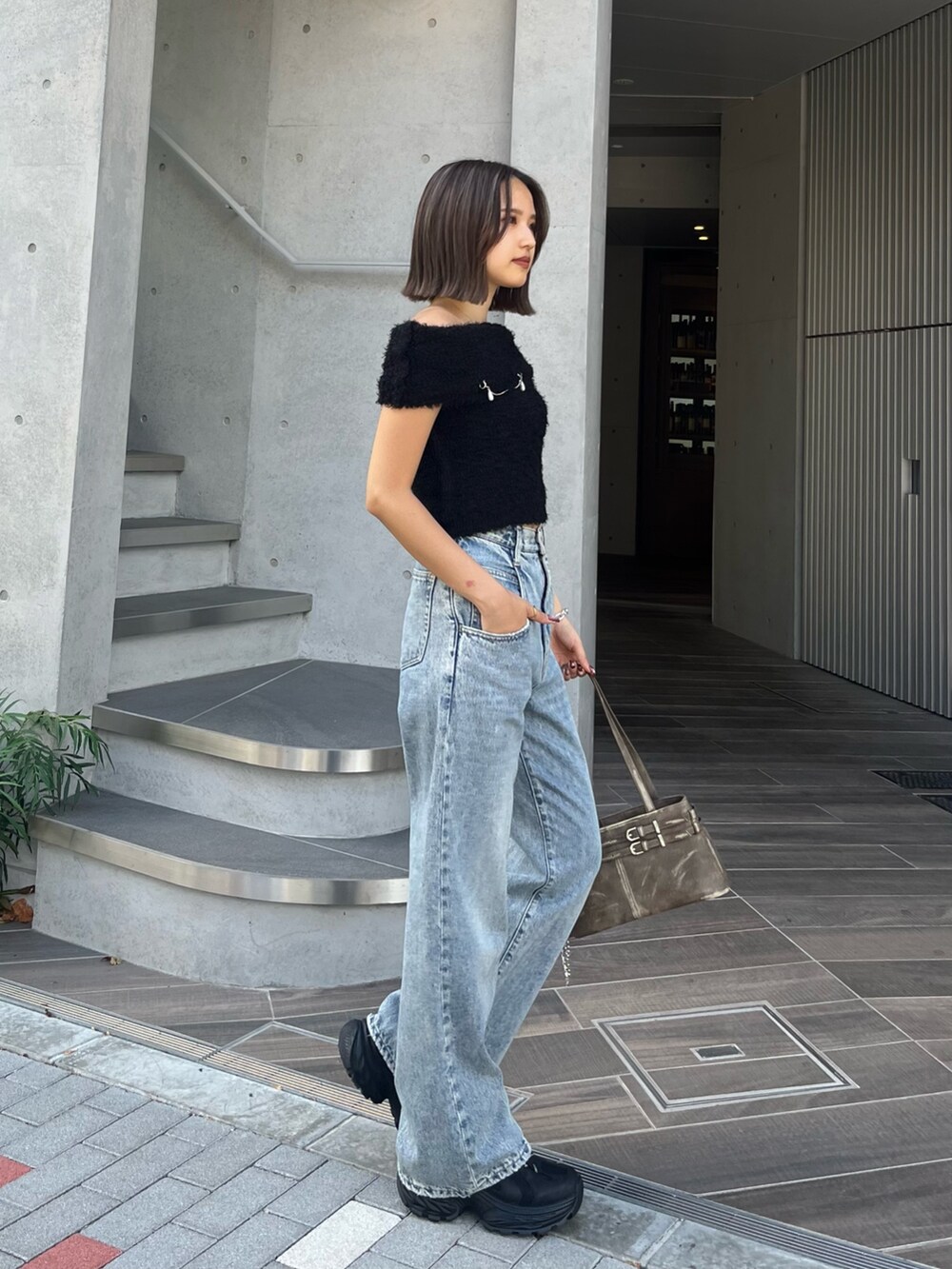 ブラウン系のハンドバッグ、ブラック系のスニーカー、ブルー系のデニムパンツを着用したレディースの夏コーディネートの2枚目の写真